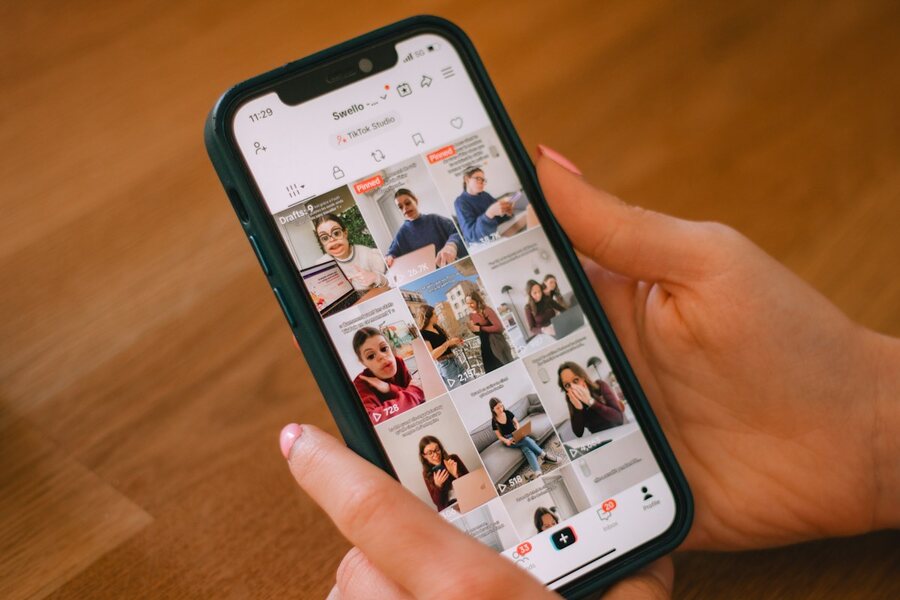 A person holding a phone displaying a social media feed.